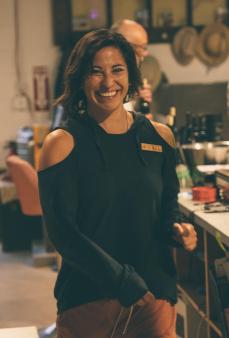 Woman with dark, bobbed hair, black sweater, in a cafe