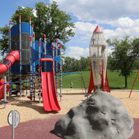 Climbing and slide structure, with a rock in the play area and the spaceship