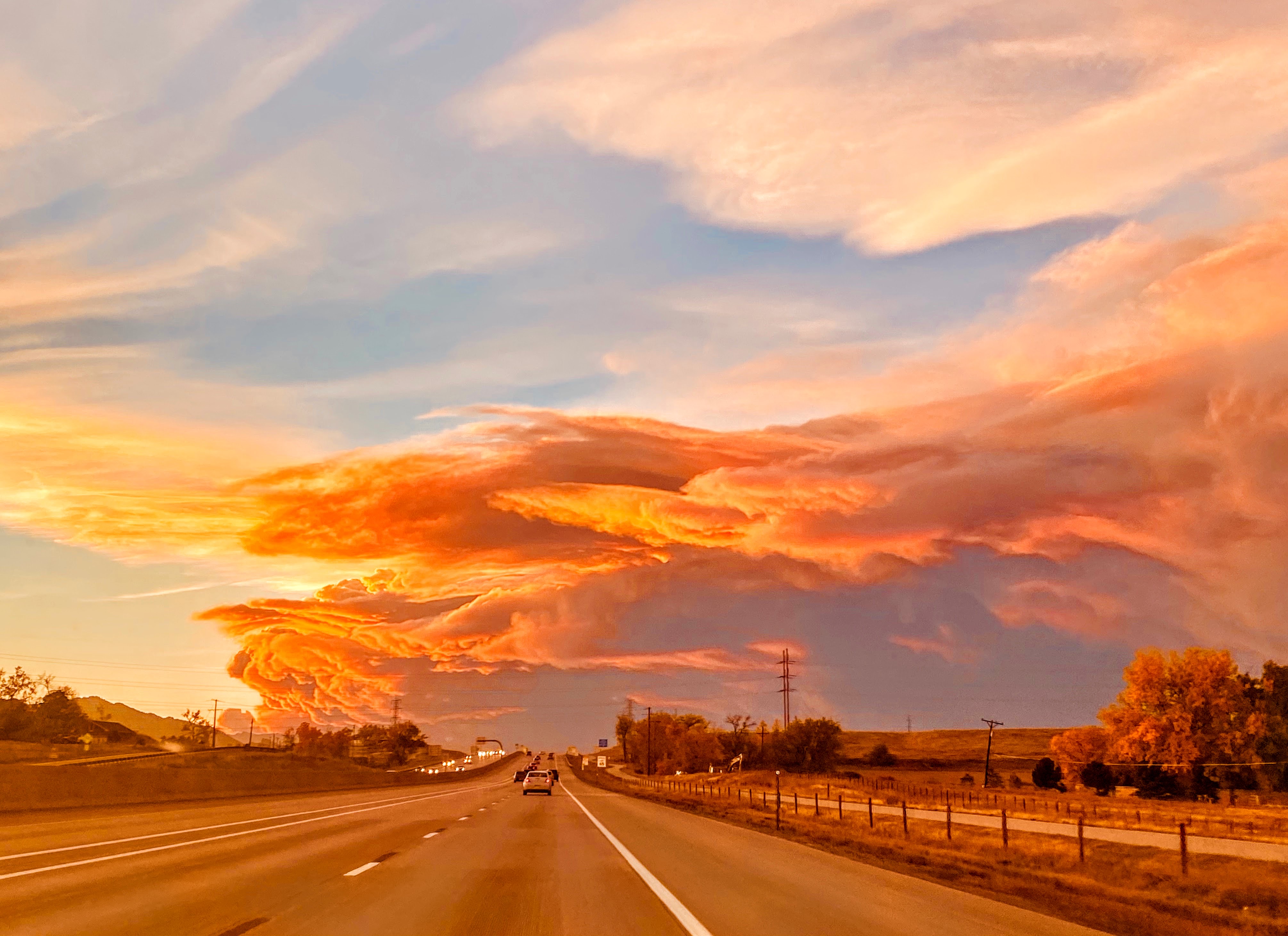 Foto de una carretera con nubes de humo rosa que se extienden por el horizonte.