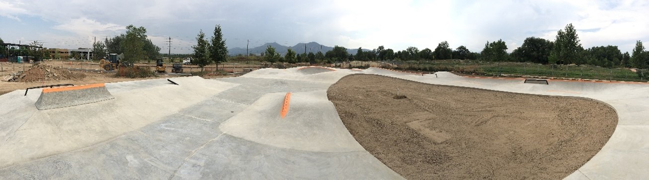 The completed concrete skate park sits empty surrounded by dirt.
