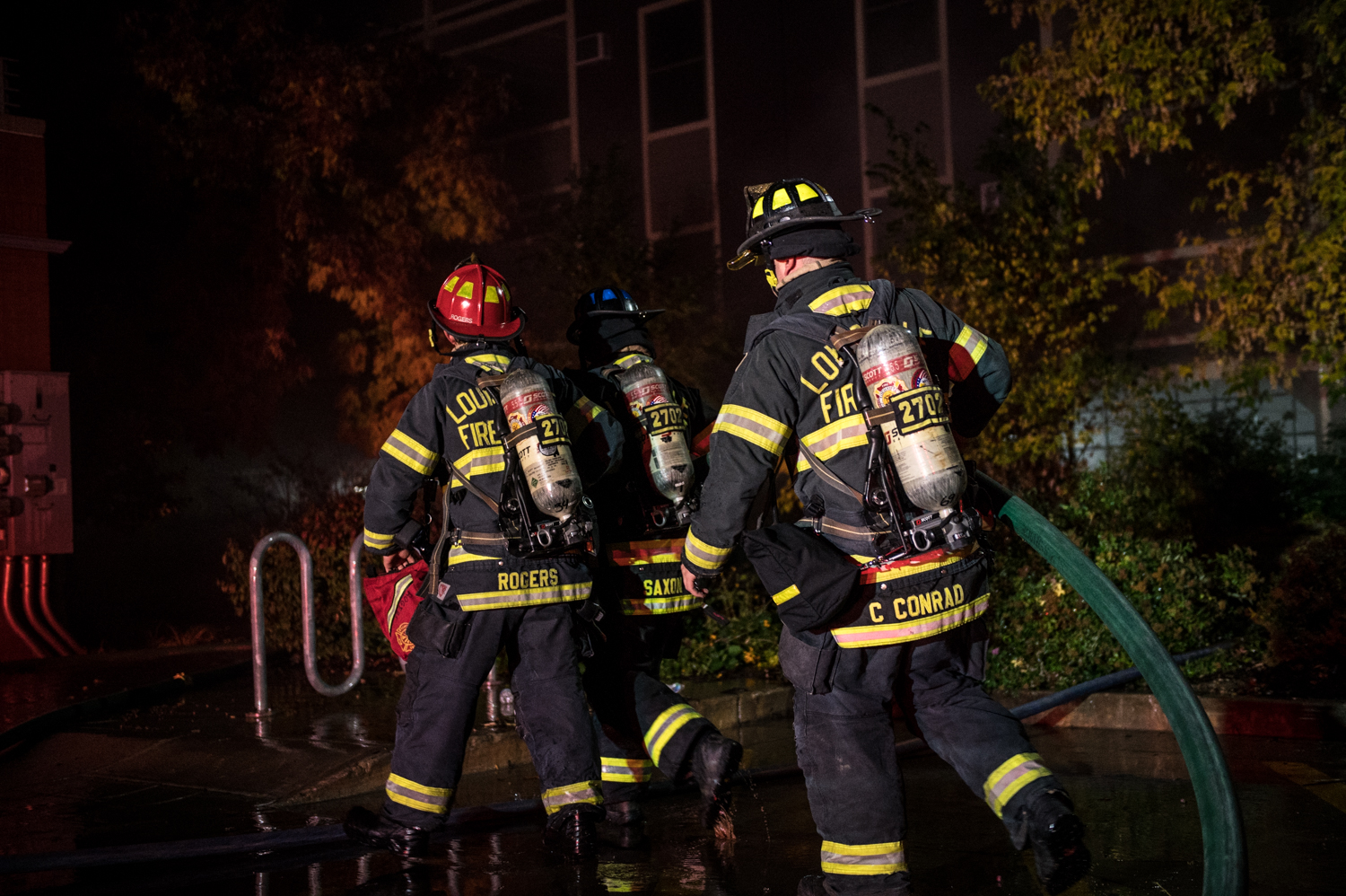 Two firefighters walking with hose to scene of fire