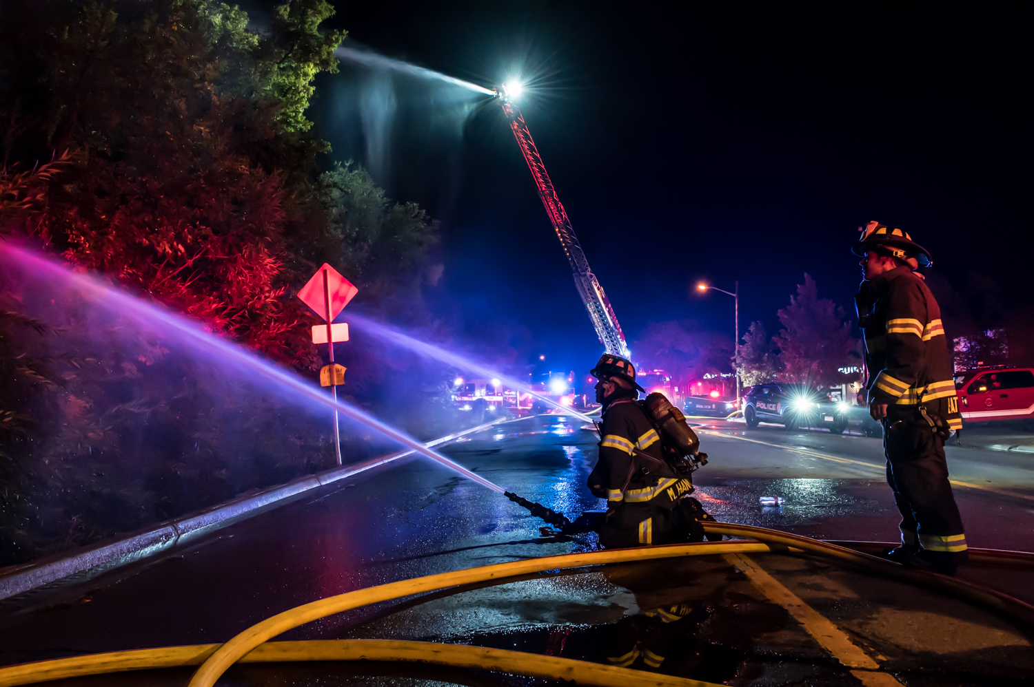 Two firefighters managing fire hoses to extinguish apartment fire