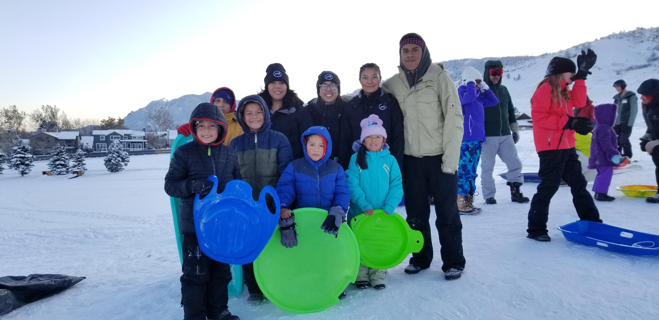 A group of Youth and Adults sleds on a snowy winter day.