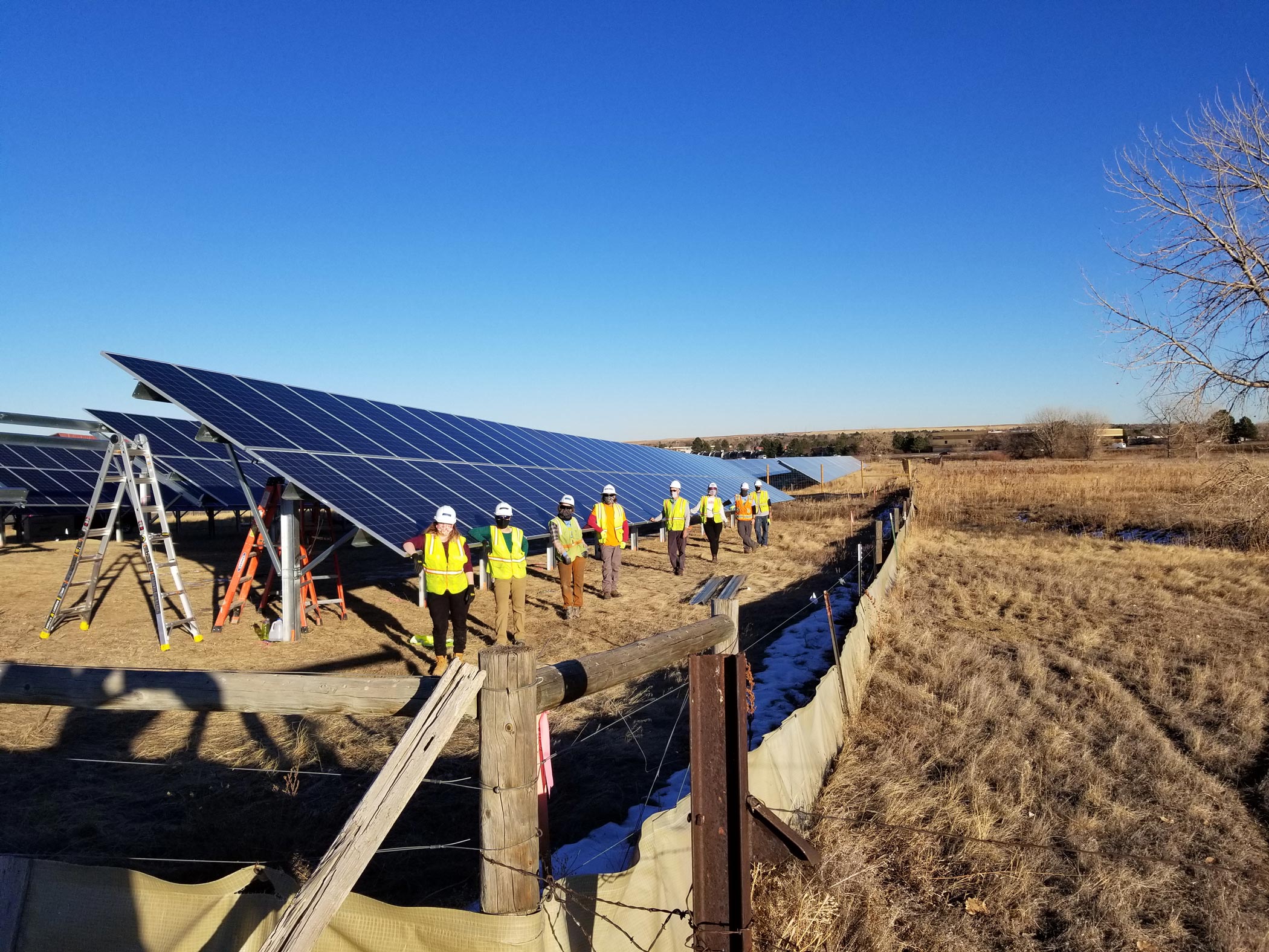 Un equipo de residentes de BHP con chalecos de seguridad amarillos instalan un jardín solar al norte de Boulder