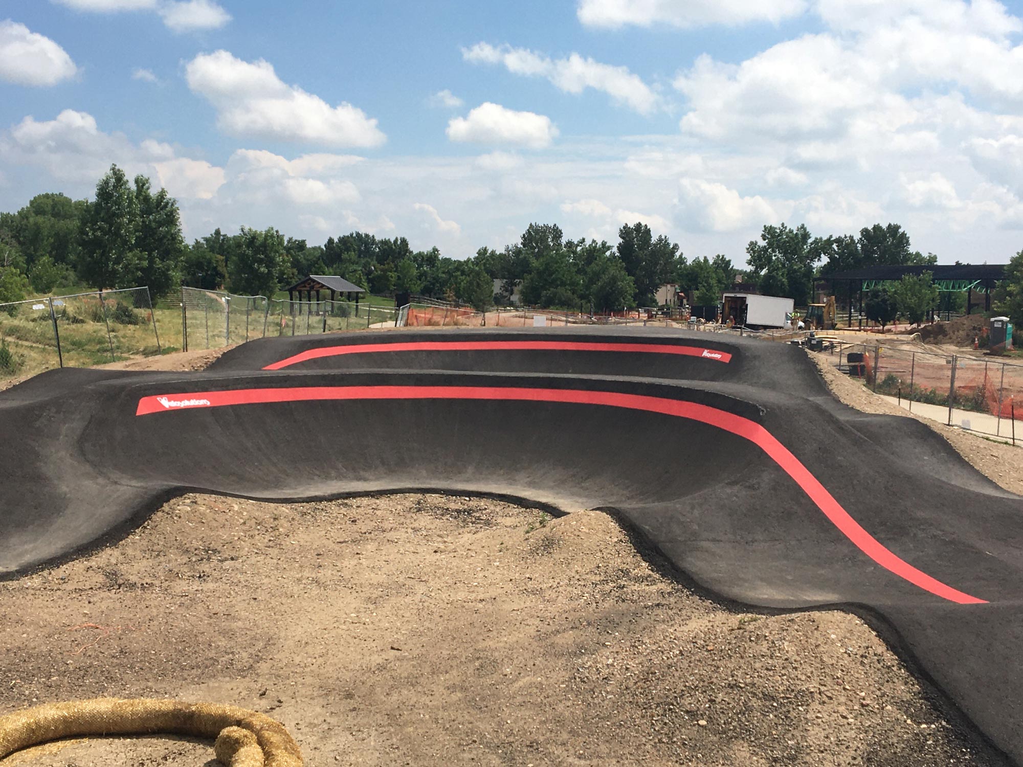 Twists and turns of black asphalt on the Valmont Pump Track, surrounded by dirt awaiting grass to seed.