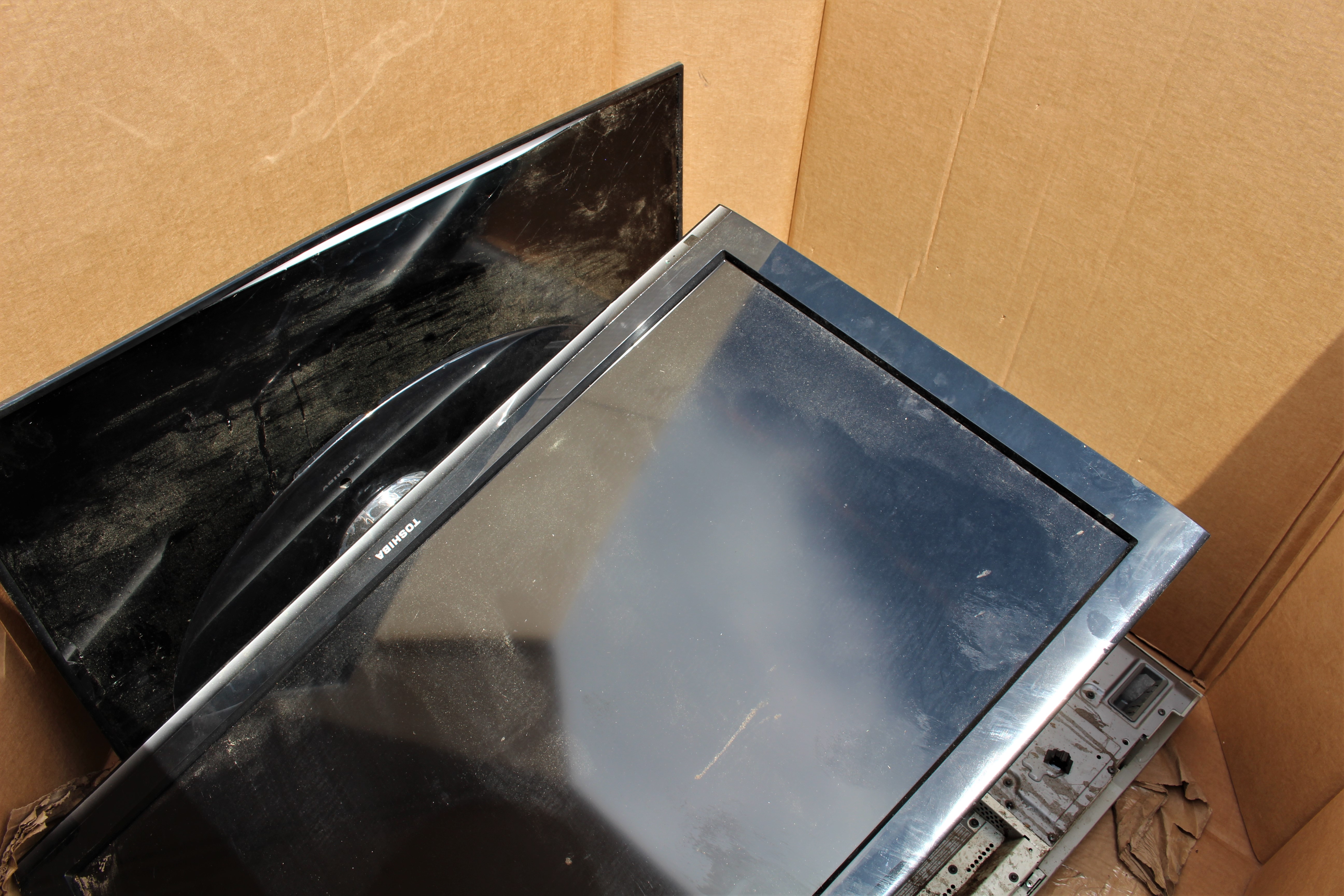 Televisions and other electronics gathered in a large cardboard box for recycling