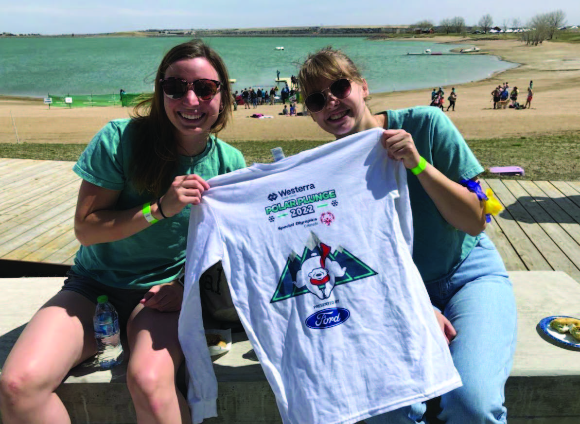 Two EXPAND interns holding up a t-shirt at the Boulder Reservoir