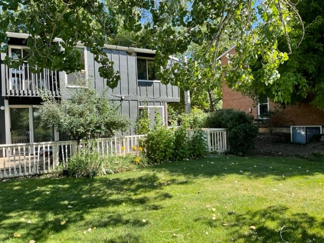 Back of unit showing greenery and white fenced in patio