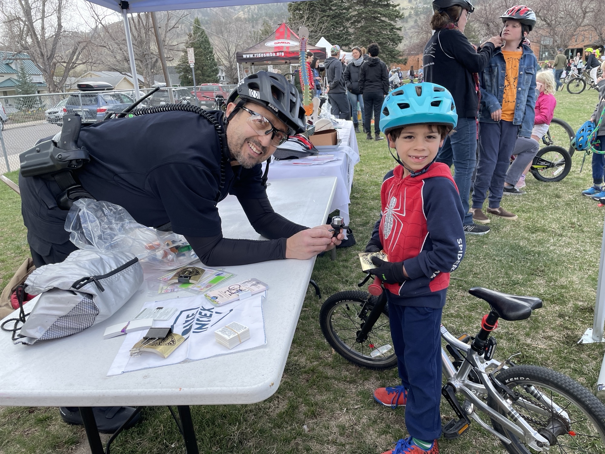 A Boulder Police Officer talking with a child wearing a helmet at a bike safety event