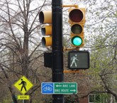 semáforo con señal de cruce de peatones, poste de tráfico y señales de orientación