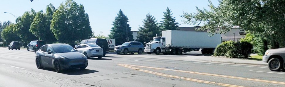 multiple cars and large semi-trucks passing the Safeway Shopping Center business access