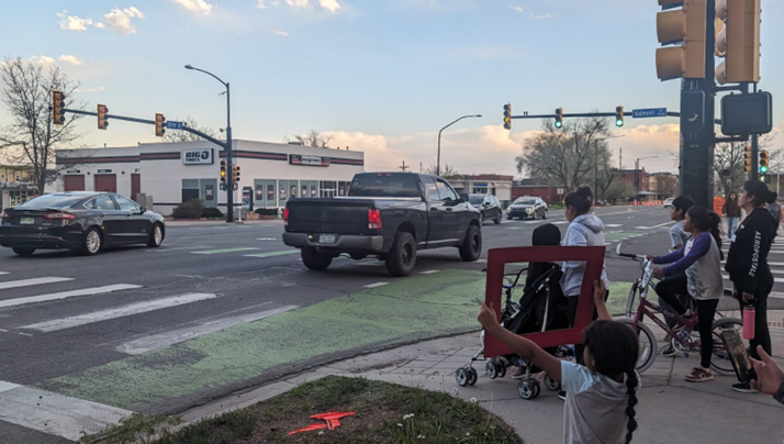 Youth using red frames at an intersection to show what they thought could be improved on 30th Street at a 2024 4/24 walk audit