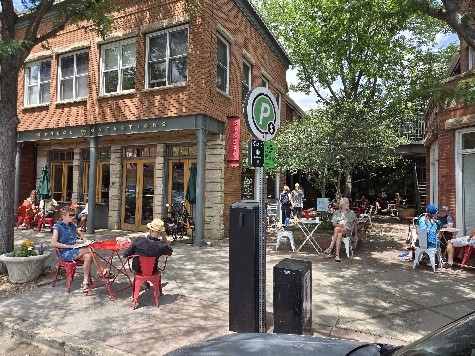 Outside of Spruce Confections. People sit in chairs outside the cafe and talk and eat.