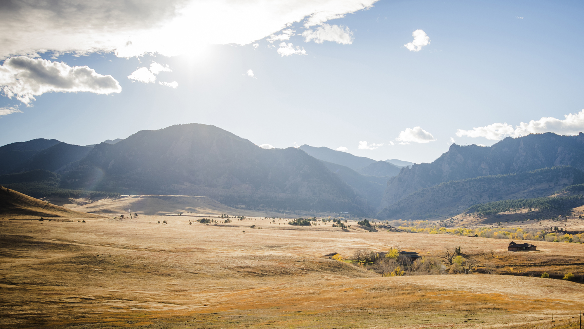 Sunlight streaks down over the Boulder Flatirons