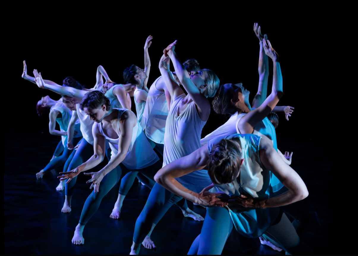 Dancers dressed in all white performing on stage