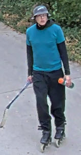 Front facing image of man in blue shirt, long sleeves, helmet and skates holding a hockey stick