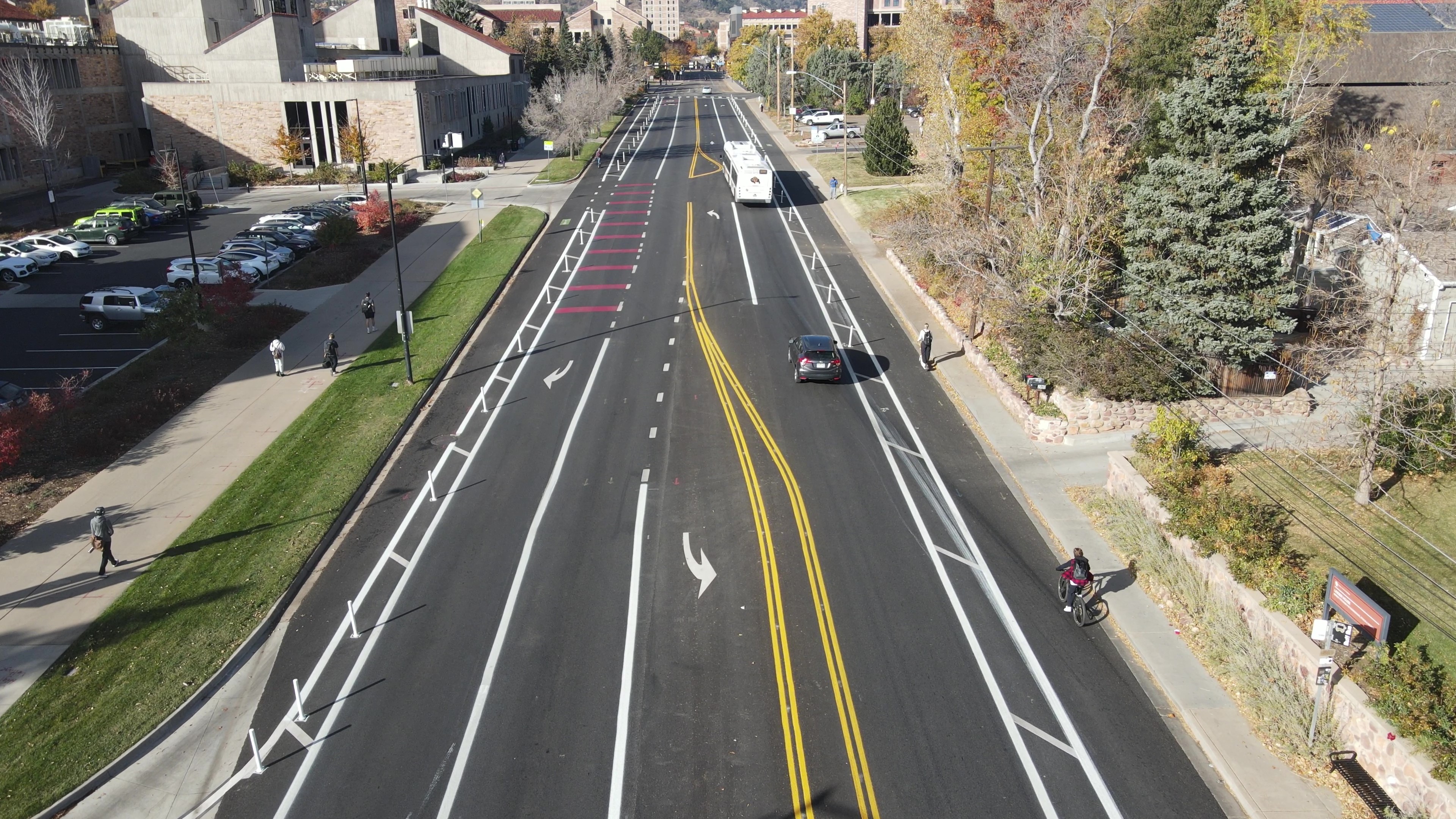 Colorado Avenue shown after 2025 mobility enhancements with wider bike lanes in each direction separated from vehicle lanes by flexible delineator posts, an eastbound bus and right turn lane, an eastbound through lane, a westbound through lane, and turn lanes at the Folsom St and Regent Dr intersections.