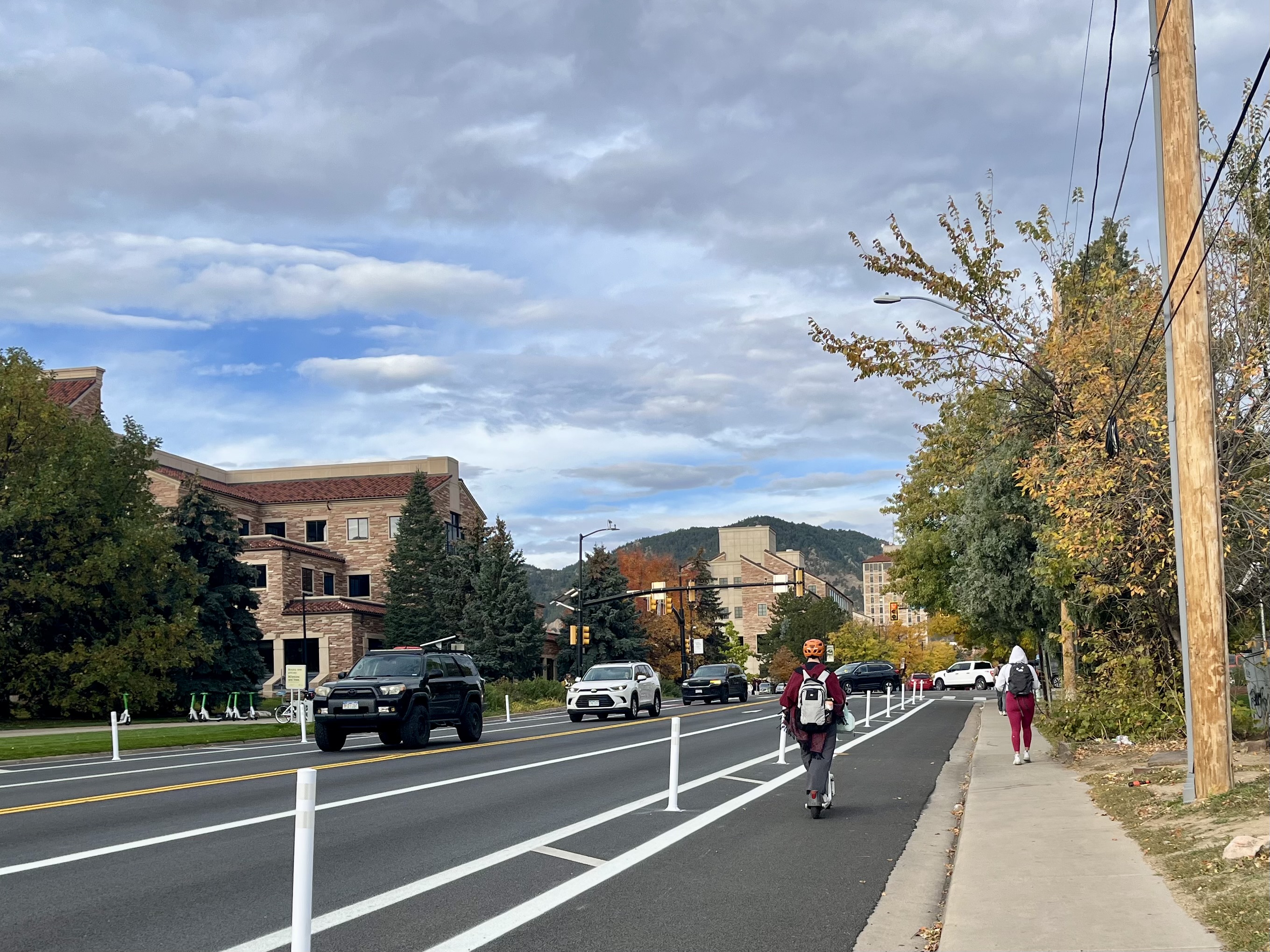 After the 2025 mobility enhancements, a person rides a Lime scooter westbound in the separated bike lane on Colorado Avenue towards the Folsom Street intersection. 