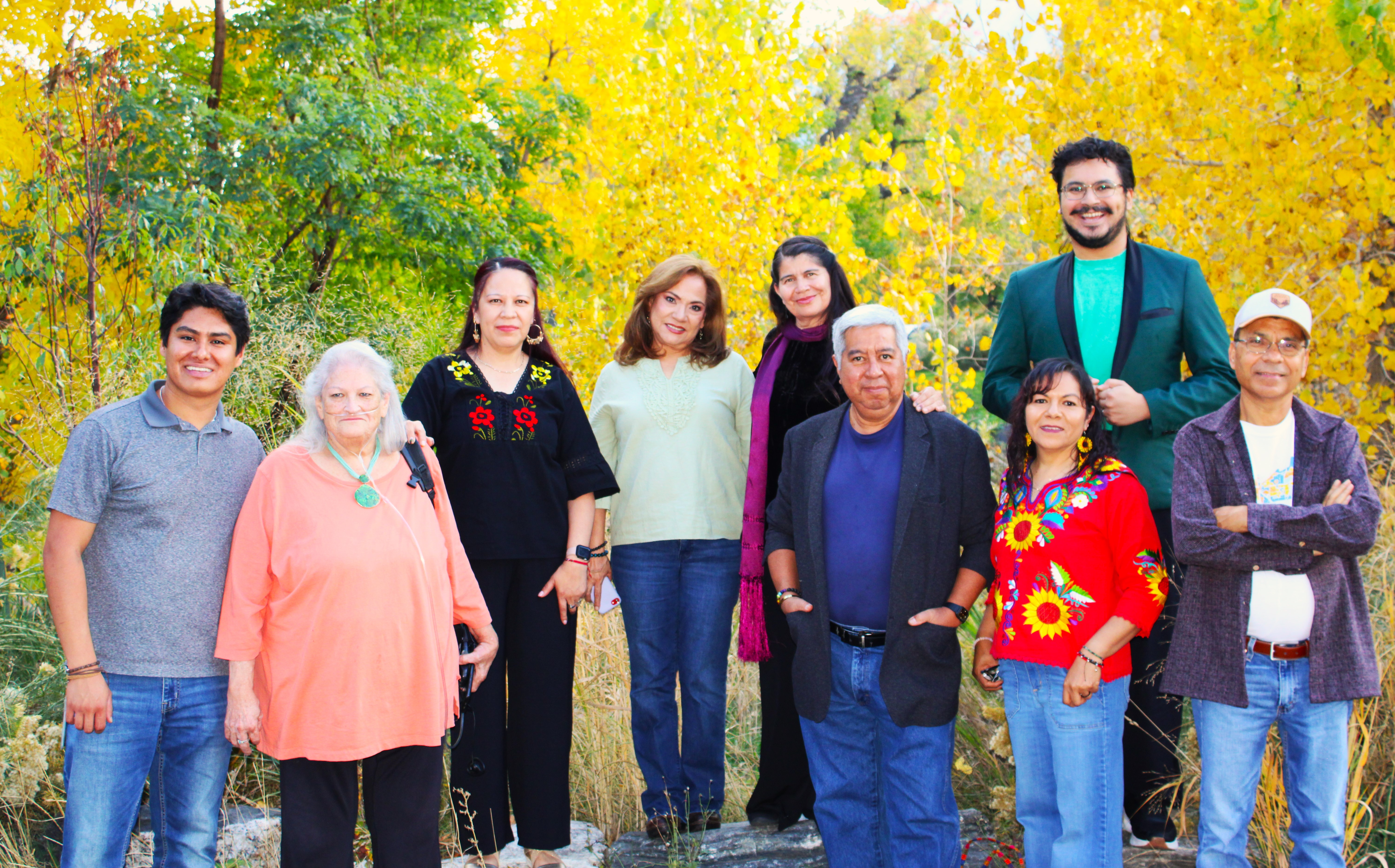 People gathered in an outdoor setting with fall foliage in the background