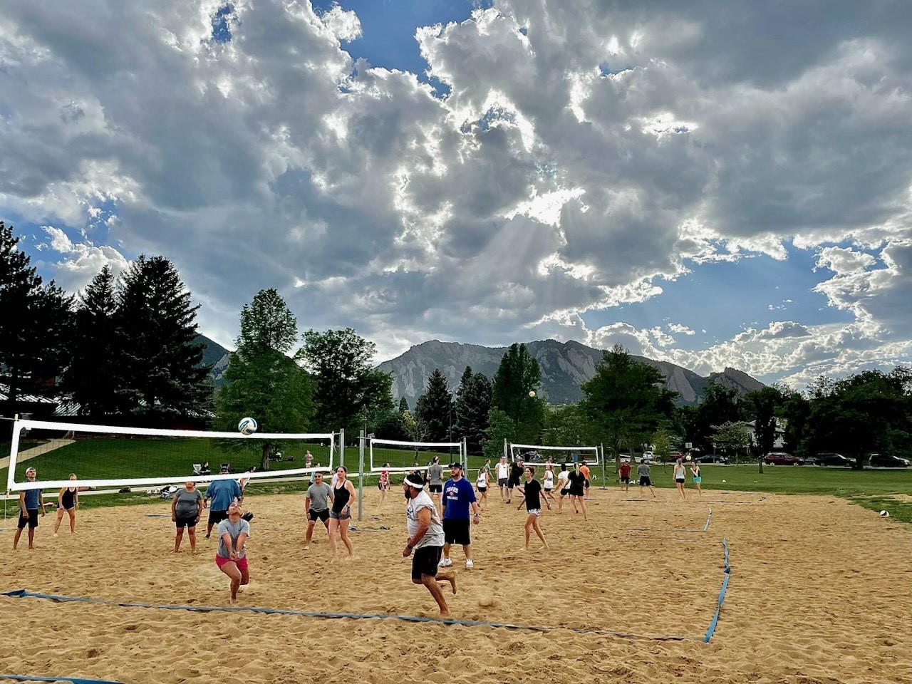 Volleyball teams playing on sand courts with mountains in the background