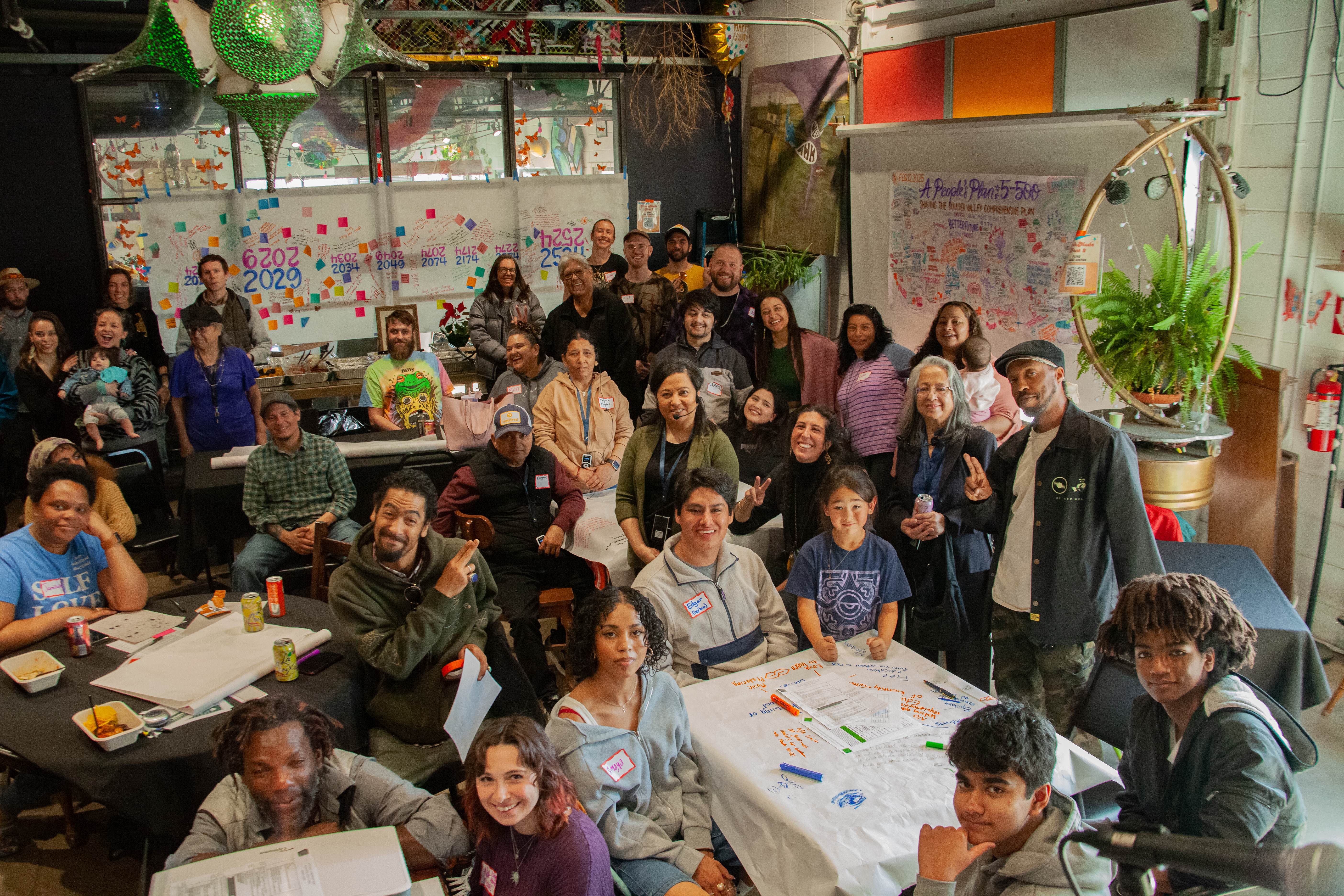 A group picture of people of all ages with tables and sticky notes. 