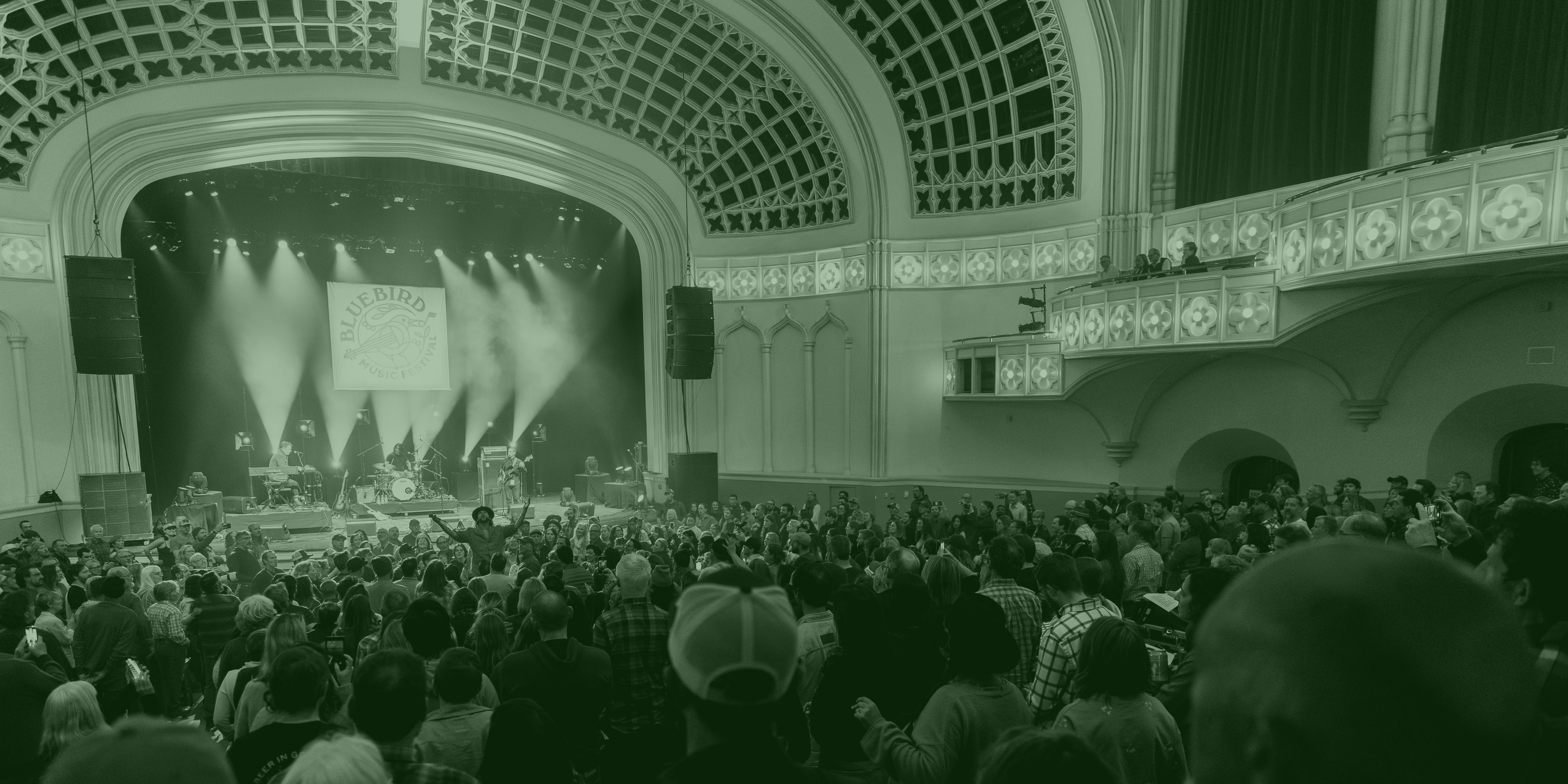 The inside of a small concert venue with audience members watching a concert on stage. 