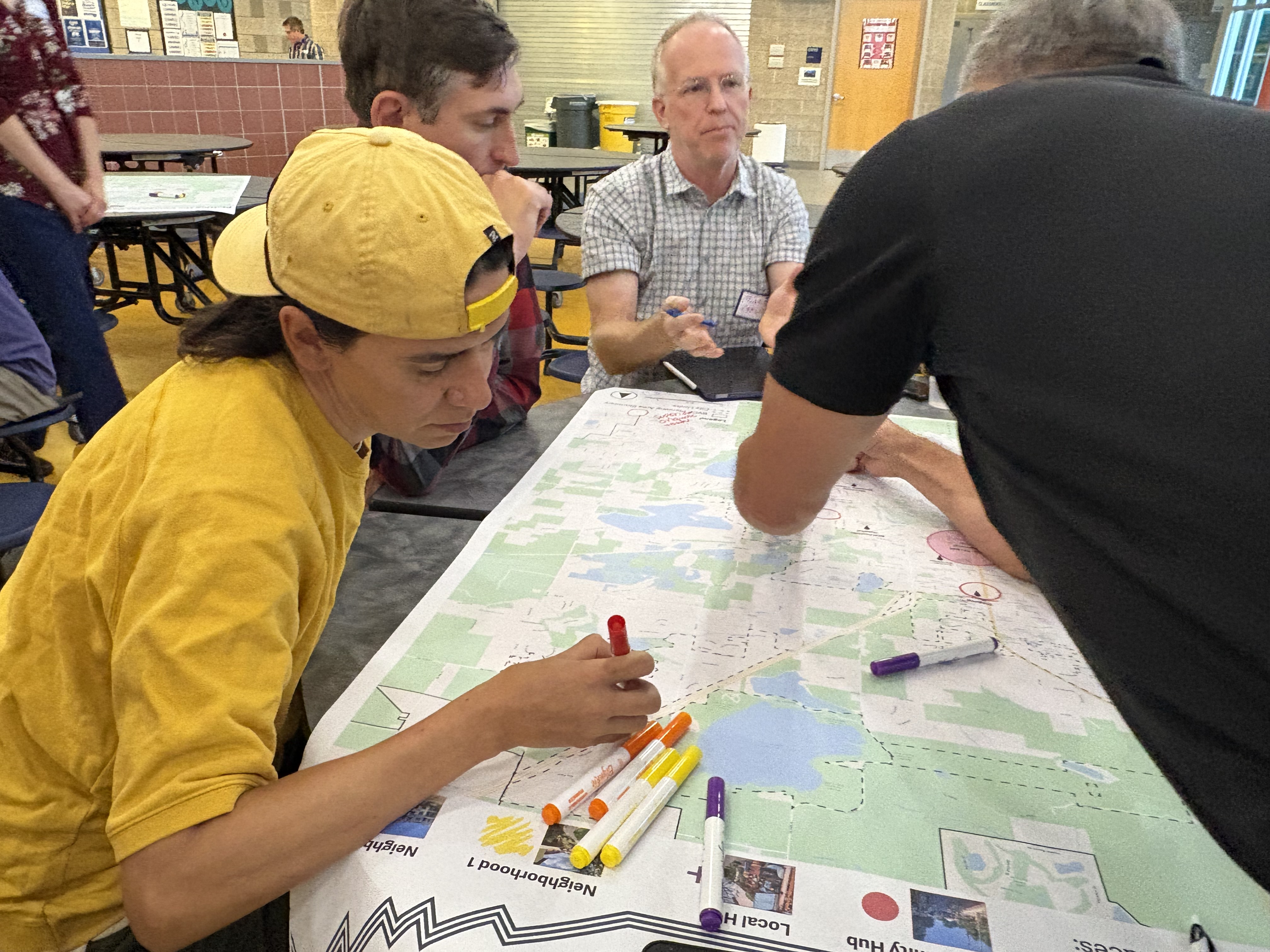 People sitting around a map making notes on it with markers.