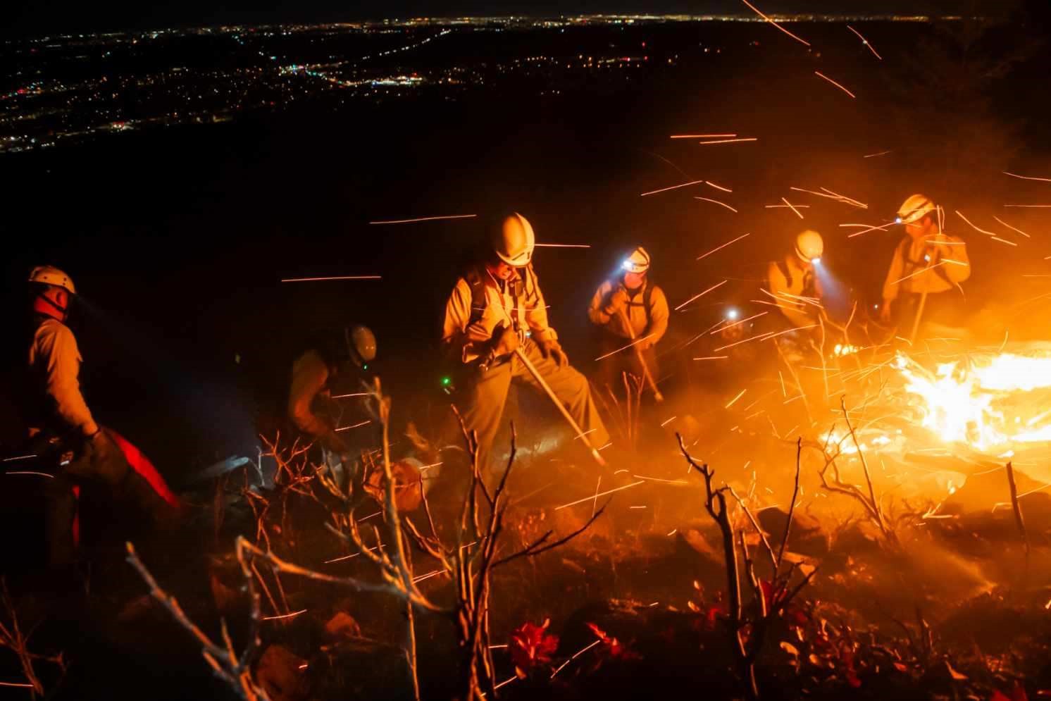 Firefighters working to put out a wildfire at night.