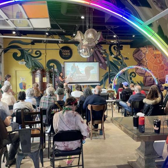 Attendees of an artist event listening to a speaker at Junkyard Social Club