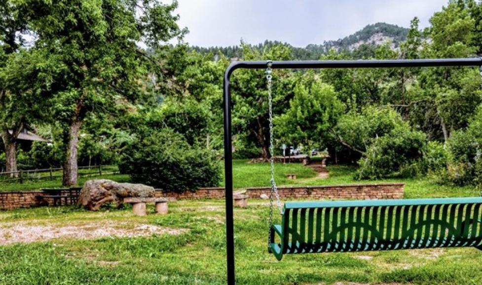bench swing facing mountain view with trees and blue sky