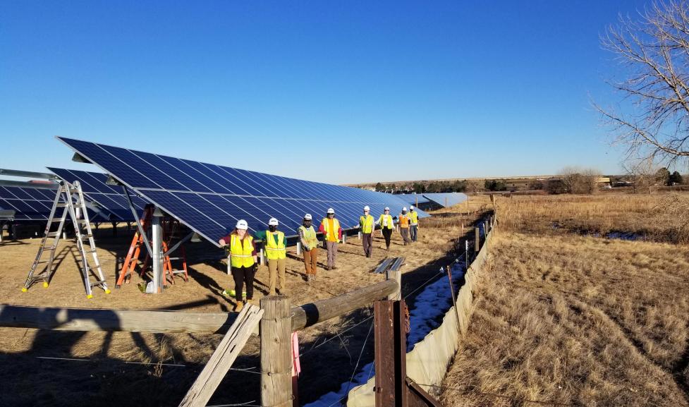 A team of BHP residents in yellow safety vests install a solar garden north of Boulder