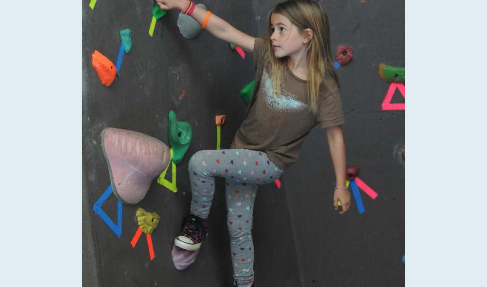 Girl bouldering at the climbing wall at the East Boulder Community Center