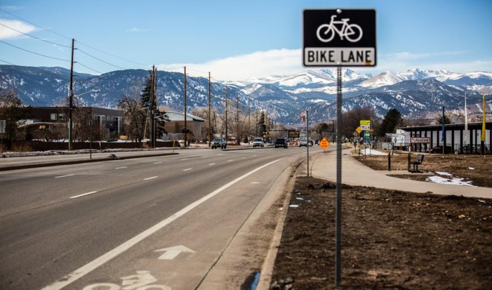 A bike lane sign next to a road with a bike lane