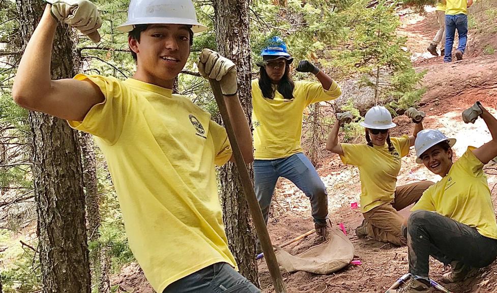 Four teenagers pose on a newly dug trail showing off their arm muscles