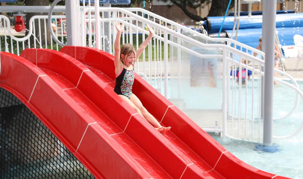 Girl sliding down the red slide at Scott Carpenter Pool