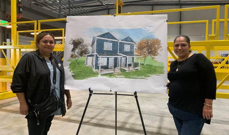 Future modular homeowners, Maribel Gonzalez and Dulce Rodriquez, standing with a rendering of the future modular homes.