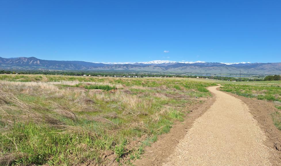 A wide gravel trail winding toward distant mountains