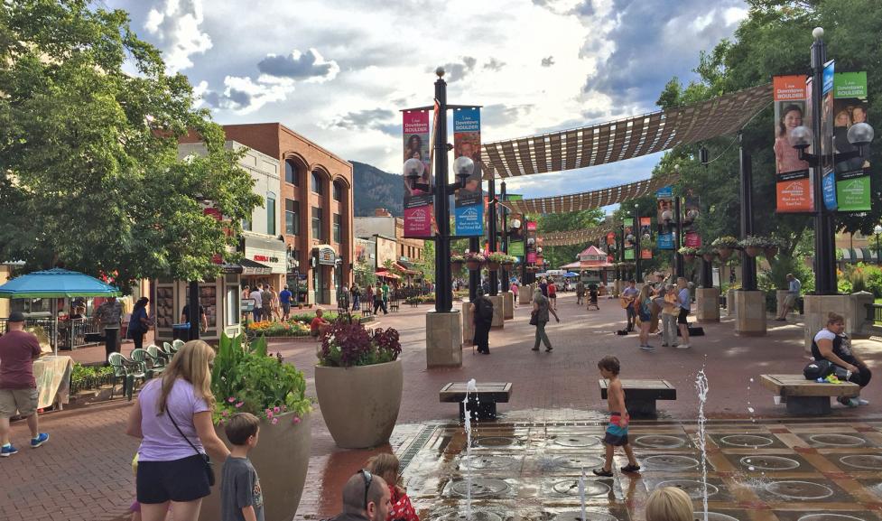 Pedestrians shopping, strolling and playing in the pop jet fountains on the Pearl Street Mall