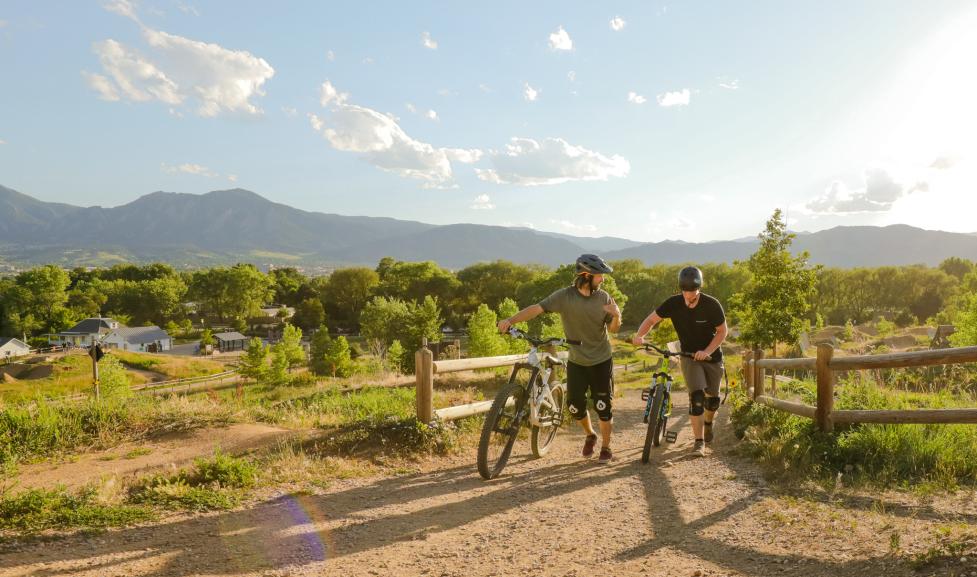 People walking with bikes at Valmont Bike Park dirt trail
