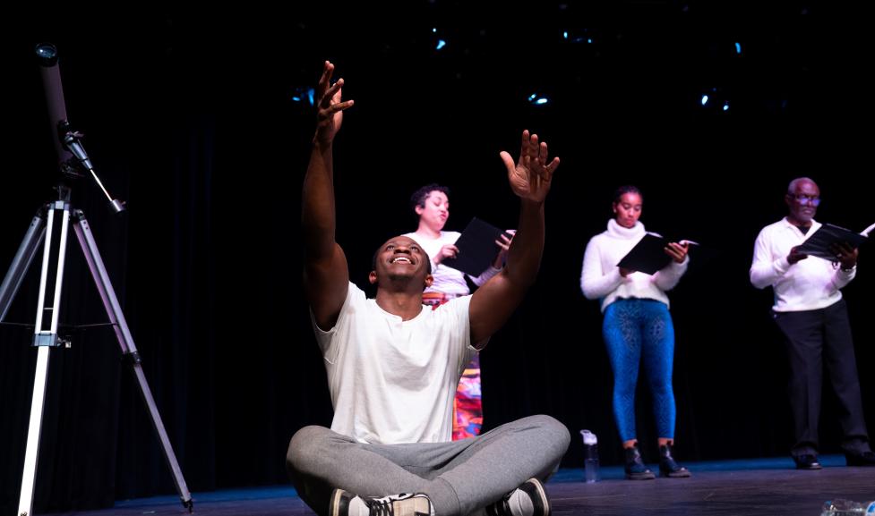 Man sitting on ground performing with hands reaching toward the sky