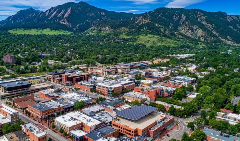 Aerial image of multi story buildings with trees and mountains in the background. 