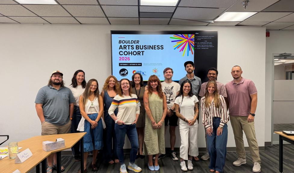 Group of artists posing in front of a powerpoint screen reading 'arts business cohort'