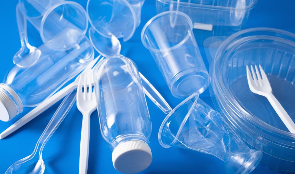 Plastic cups, utensils and containers on a blue background