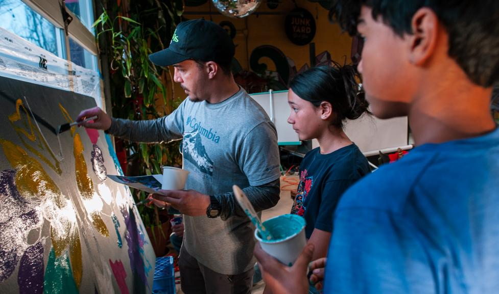 Painter working on a mural with the help of kids