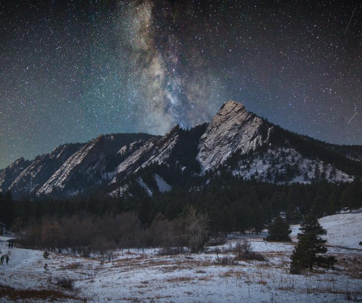 a beautiful bright starry sky over the flatirons covered with snow in winter