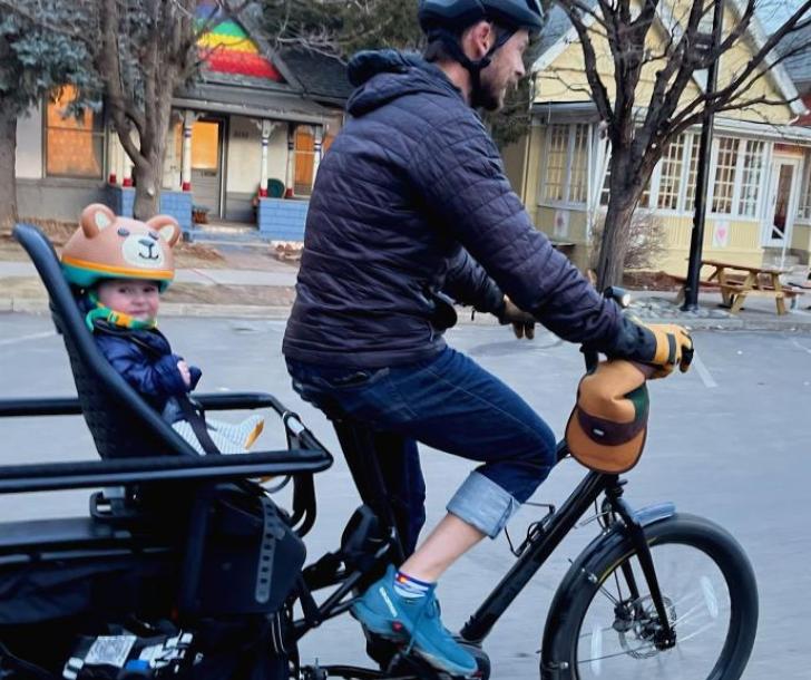 A man riding his e-bike with a child in the backseat