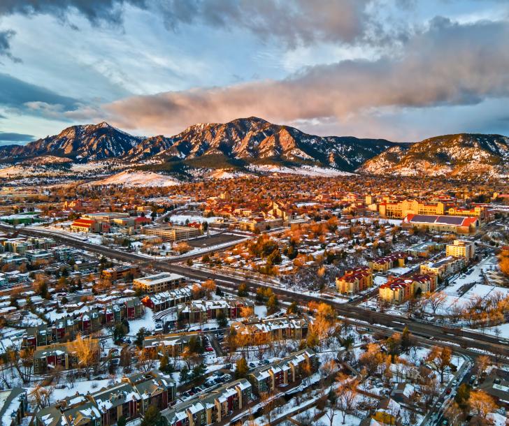 Aerial view of City of Boulder toward the Flatirons at dusk with a dusting of snow