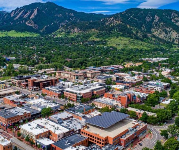 Aerial image of multi story buildings with trees and mountains in the background. 