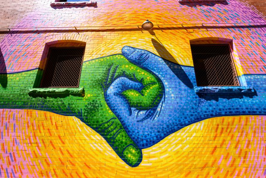 Mural of a blue hand holding a green hand
