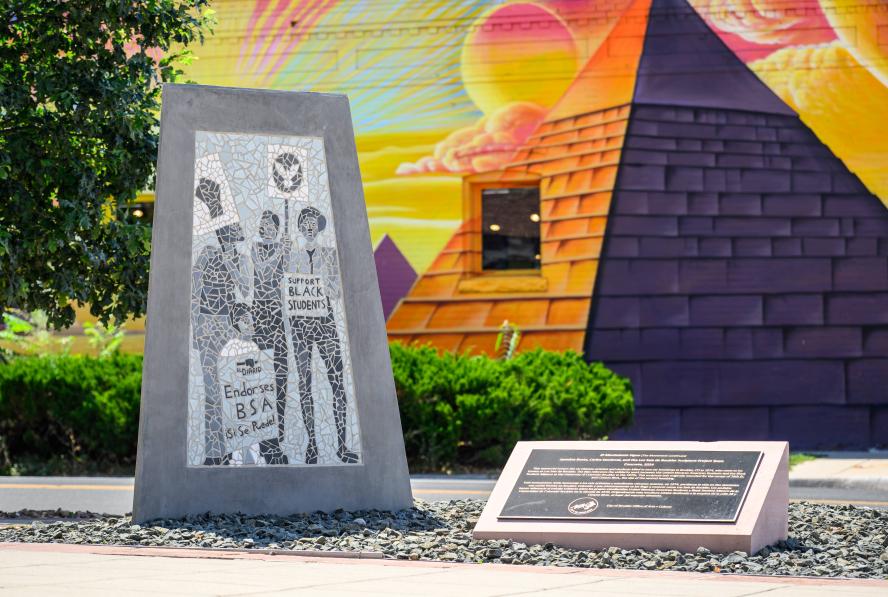 El Movimiento Sigue sculpture in front of a colorful mural